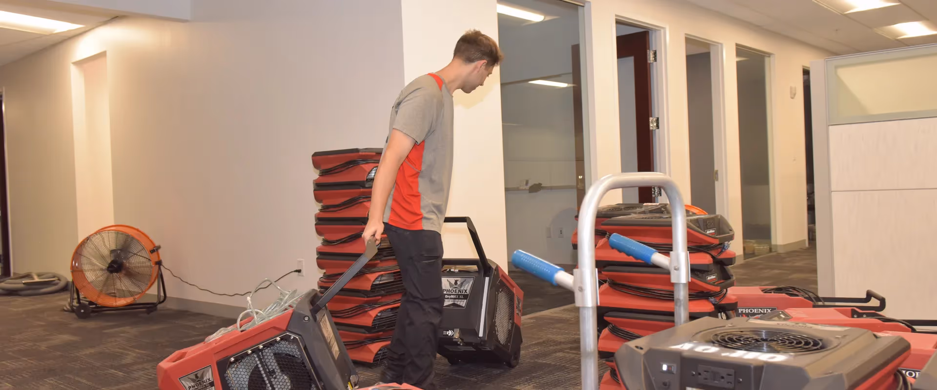 Technician setting up stacked red air movers in a commercial office space
